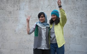 This picture taken and released by the Sharq News Online on January 14, 2024, shows Iranian journalists Niloufar Hamedi (R) and Elaheh Mohammadi (L) flashing the sign of victory after they were released from Evin prison on bail in Tehran.