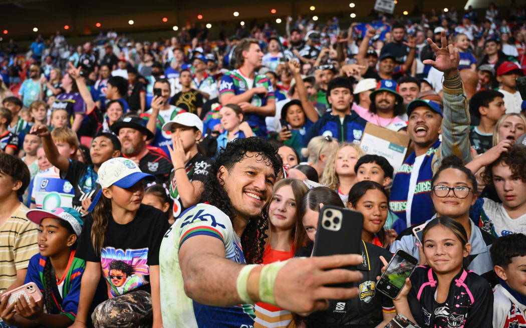 Dallin Watene-Zelezniak of the Warriors takes a selfie with fans.