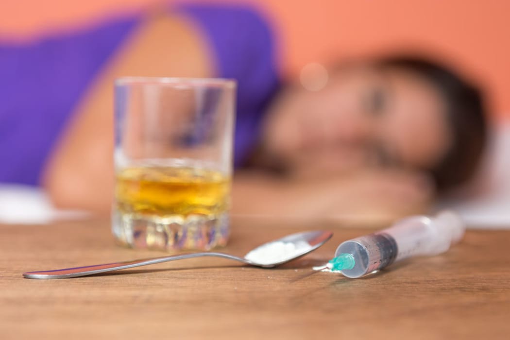 A glass of alcohol and a syringe.