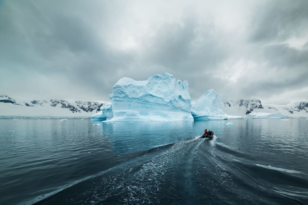 A small inflatable boat heads out to the iceberg Lincoln