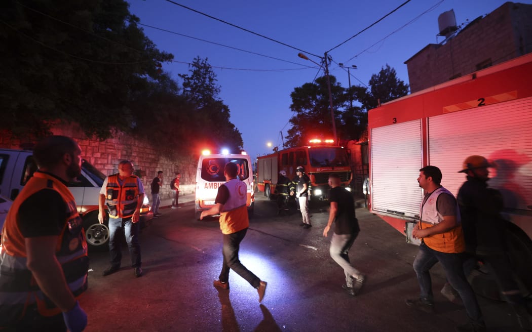 EDITORS NOTE: Graphic content / Palestinian Red Crescent rescuers rush to evacuate the wounded during clashes between Israeli troops and Palestinian gunmen in the Old City of Nablus in the northern occupied West Bank early on July 24, 2022. - Two Palestinians were killed and six others wounded overnight during an Israeli army raid on Nablus, according to the Palestinian health ministry. The Israeli army confirmed carrying out an operation in the area in a statement which said there were exchanges of fire between armed suspects and troops. (Photo by JAAFAR ASHTIYEH / AFP)
