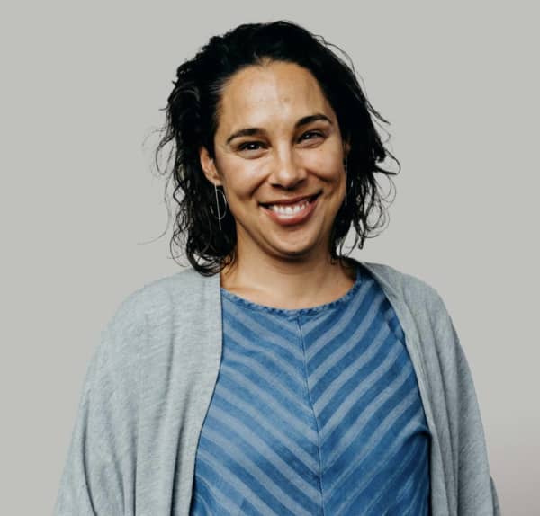 Kristin Ward is a smiling, dark-haired woman wearing a blue striped top and a grey cardigan.