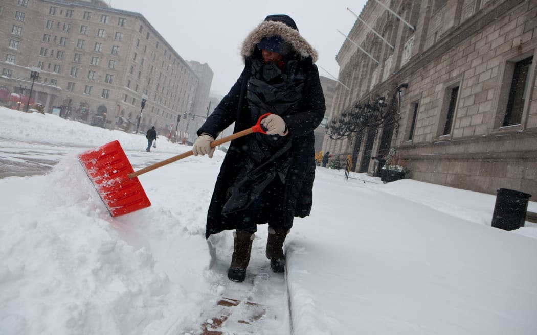 A library employee works to clear the sidewalks in front of the main branch of the Boston Public Library during a blizzard on 27 January 2015 in Boston, Massachusetts.