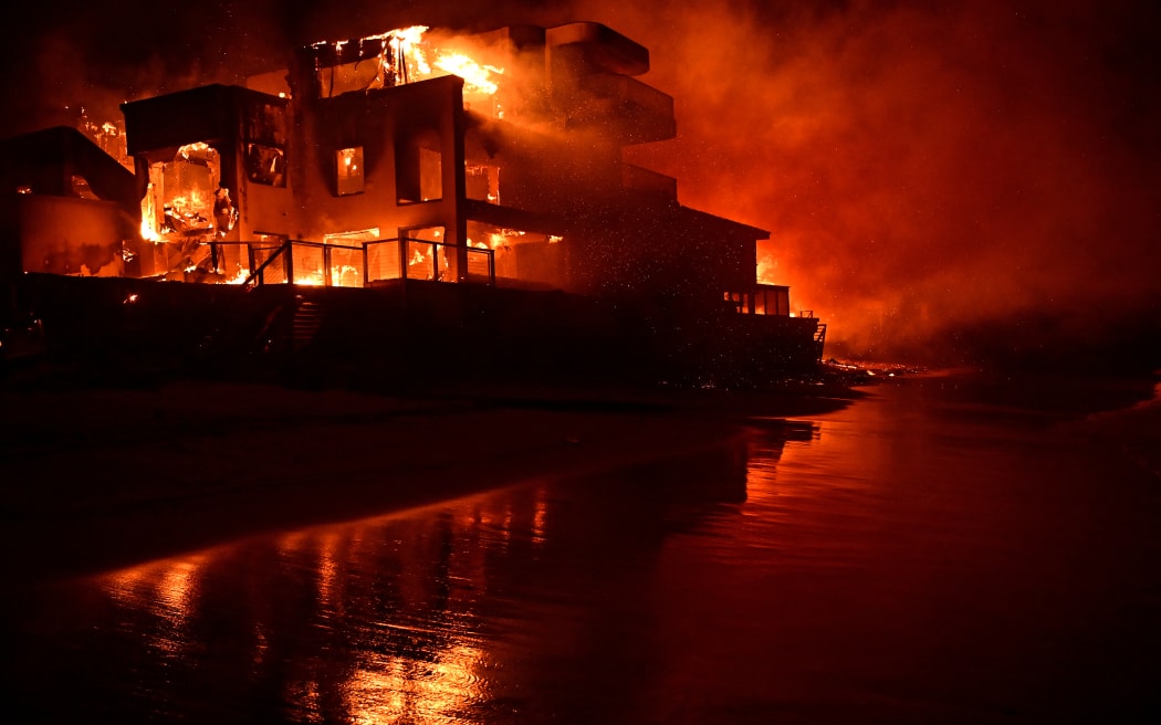 A beach house is engulfed in flames as the Palisades Fire burns along Pacific Coast Highway in Malibu, California, on January 8, 2025. - At least five people have been killed in wildfires rampaging around Los Angeles, officials said on January 8, with firefighters overwhelmed by the speed and ferocity of multiple blazes -- including in Hollywood. (Photo by AGUSTIN PAULLIER / AFP)