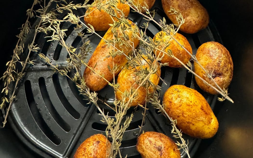 Skin on roast potatoes sitting in an air fryer.