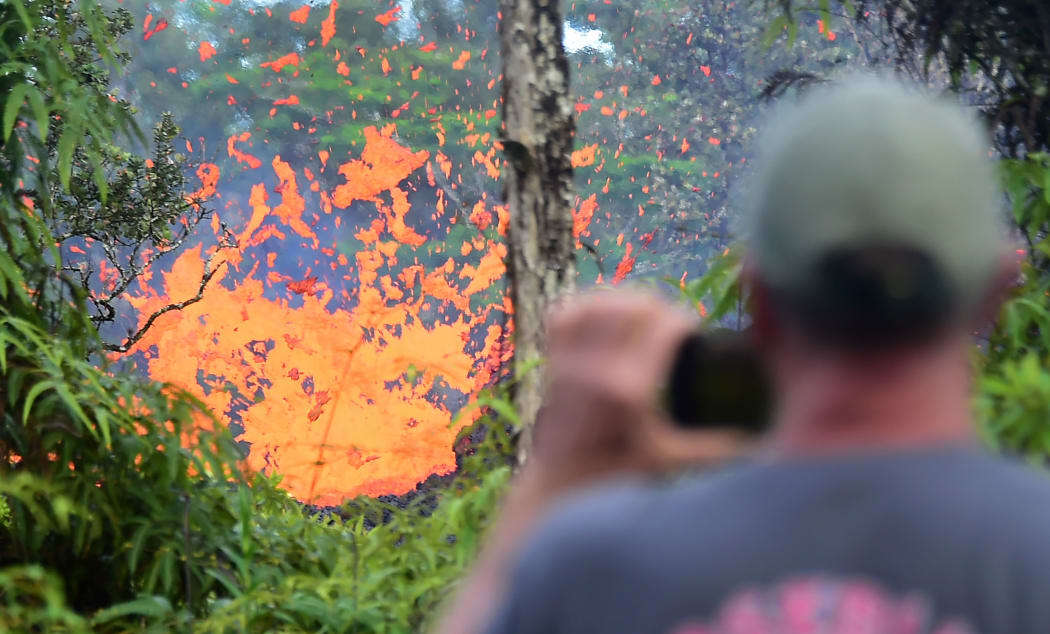 A man watches as lava is seen spewing from a fissure in the Leilani Estates subdivision near the town of Pahoa on Hawaii's Big Island on May 4, 2018. / AFP PHOTO / Frederic J. BROWN