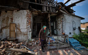 Tatyana, 69, walks in front of her destroyed house in the village of Lukashivka, Chernihiv region, on September 7, 2022, amid the Russian invasion of Ukraine. (Photo by SERGEI CHUZAVKOV / AFP)