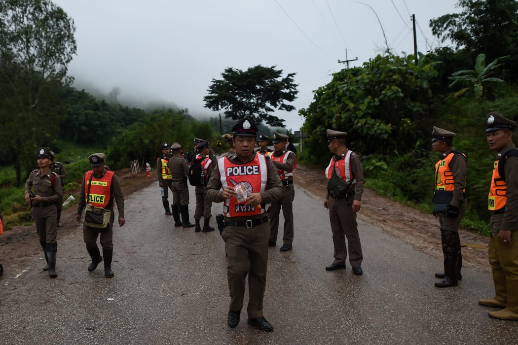 Thai police guard a road leading to the Tham Luang cave area as operations continue for the remaining eight boys and their coach trapped at the cave in Khun Nam Nang Non Forest Park in the Mae Sai district of Chiang Rai province on July 9, 2018.