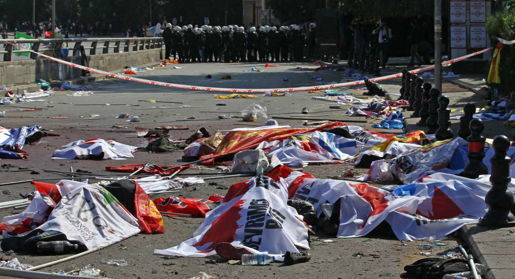 Turkish riot police forces secure the site of twin explosions. Victims' bodies are covered with banners and flags, Ankara, October 10, 2015.
