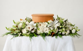 Flowers on a table with cremation urn of ashes.