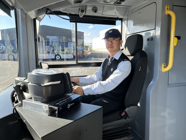 A bus driver sitting in the driver seat on a bus.