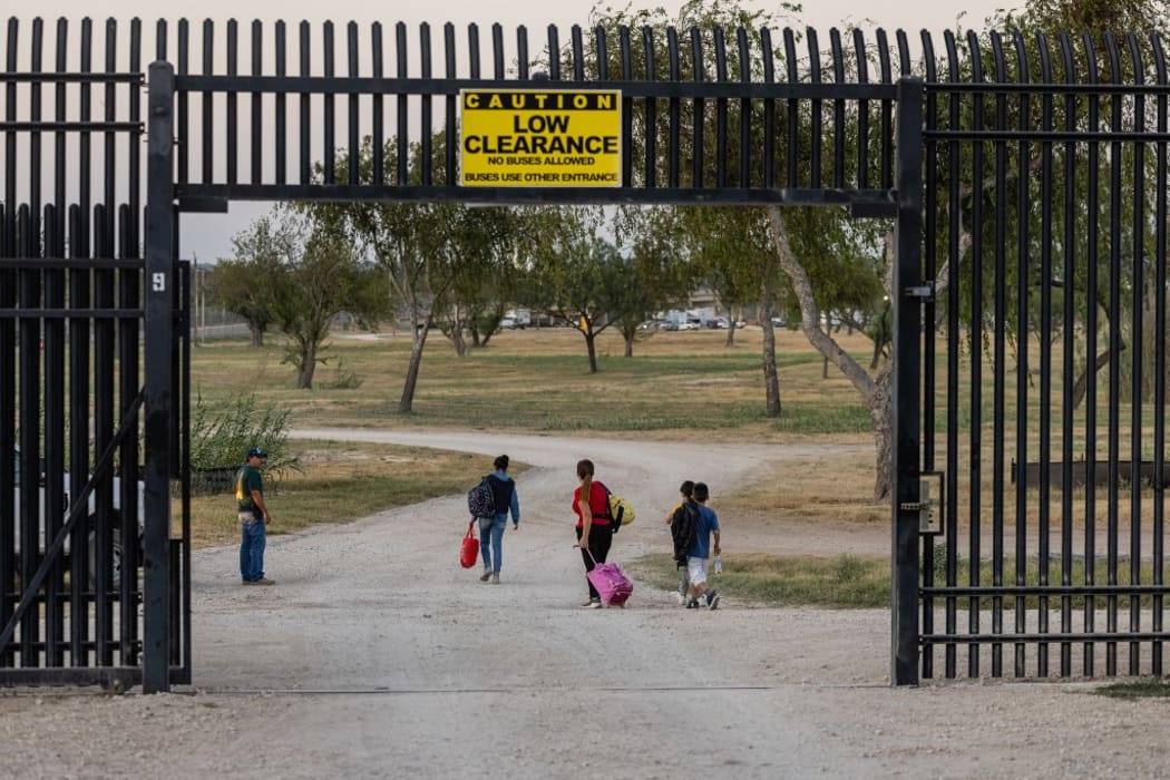 A family from Venezuela walks into the migrant camp under the international bridge in Del Rio, Texas.