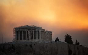 This photograph shows the Parthenon temple atop the Acropolis hill in a smoke cloud from a wildfire, in Athens on August 12, 2024. On August 12, 2024, Greece's civil protection authorities ordered the evacuation of several towns in the north-eastern suburbs of Athens, threatened by a violent fire that started the day before and is spreading. (Photo by Angelos TZORTZINIS / AFP)