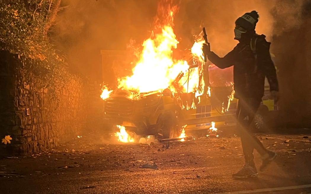 A protester films and a police vehicle burns in the background as a demonstration outside a hotel housing asylum seekers turns violent in Saggart, south-west of Dublin.