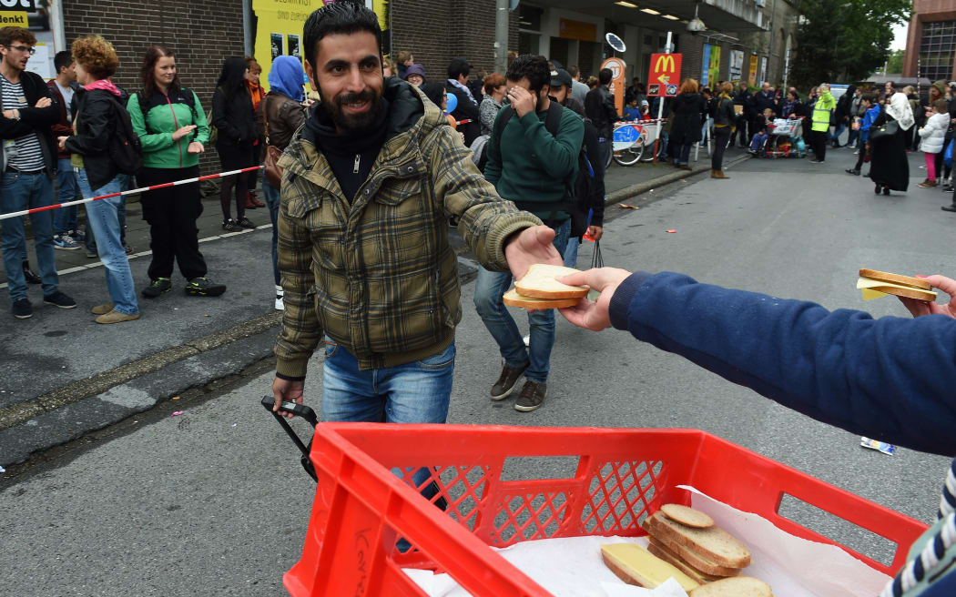 A refugee is handed food as he walks to get a bus after his arrival at the train station in Dortmund, western Germany.