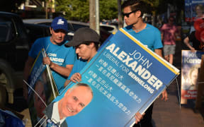 Supporters of Liberal MP John Alexander pack away banners outside a polling station at the close of votin.