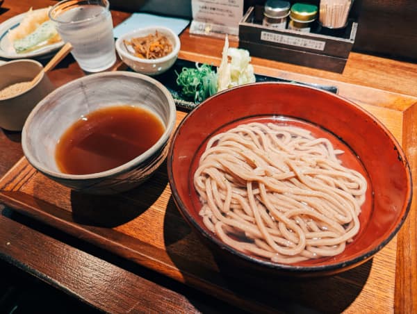 A soba udon noodle dish in Japan, with two bowls on a bamboo tray. One for the noodles, other with sauce.