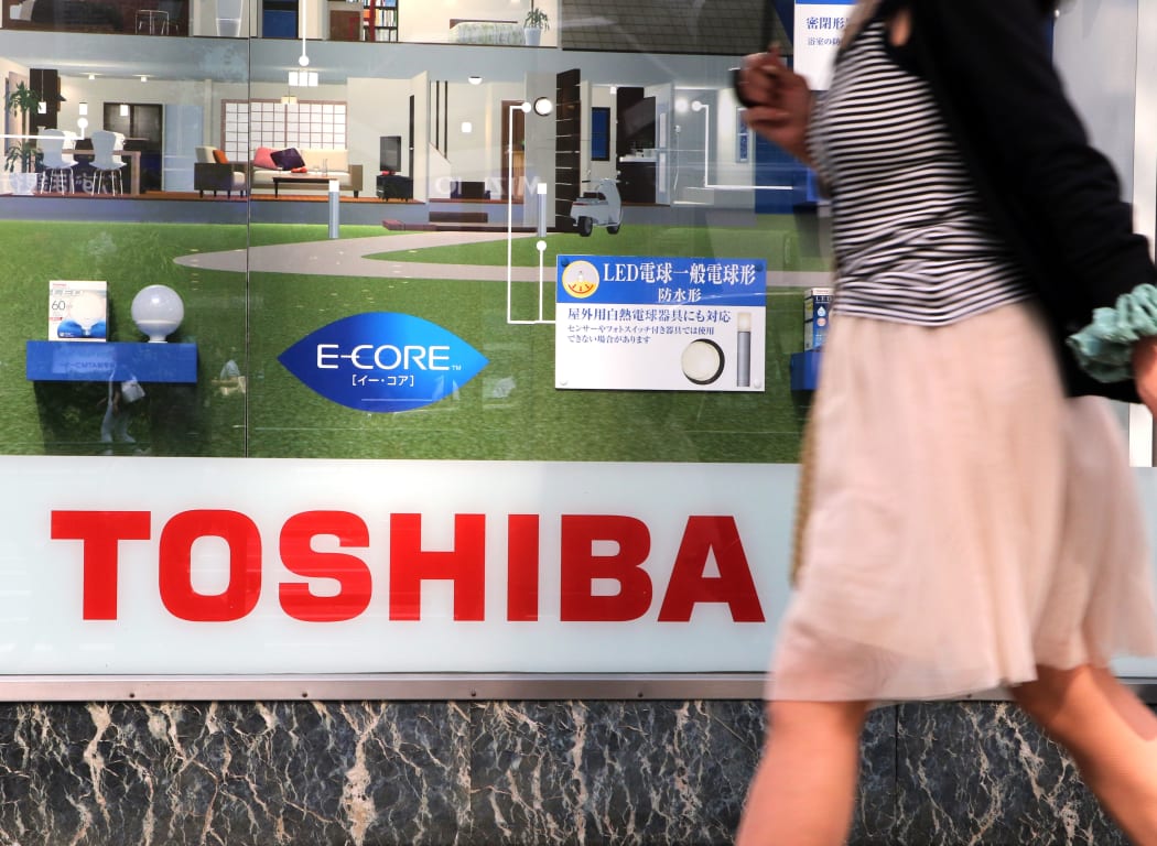 A pedestrian walks outside a Toshiba store in Tokyo on 21 July 2015.