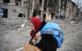 8161100 08.04.2022 An elderly woman passes by a destroyed house in Mariupol, Donetsk People's Republic. Ilya Pitalev / Sputnik (Photo by Ilya Pitalev / Sputnik / Sputnik via AFP)