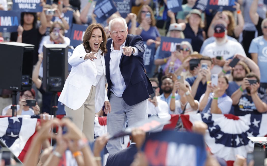 US Vice President and 2024 Democratic presidential candidate Kamala Harris and her running mate Minnesota Governor Tim Walz wave to supporters as they depart after speaking during a campaign rally in Eau Claire, Wisconsin, August 7, 2024.  (Photo by KAMIL KRZACZYNSKI / AFP)