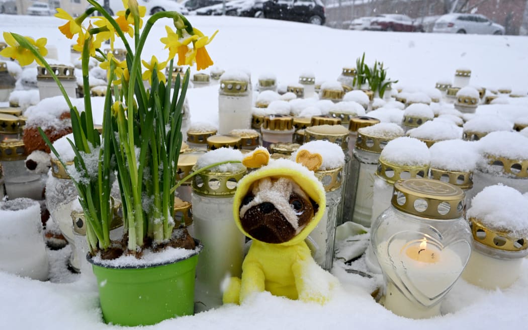 Candles and flowers are placed on a square in front of the Viertola School to pay tribute to victims in Vantaa, in the north of  the Finnish capital Helsinki, on April 3, 2024, one day after a 12-year-old opened fire inside the school, killing a classmate and seriously injuring two other children. Finland will fly its flags at half-mast on April 3, 2024, to mark the country's mourning after a 12-year-old opened fire at a school, killing one classmate and seriously injuring two others in the city of Vantaa. (Photo by Jussi Nukari / Lehtikuva / AFP) / Finland OUT