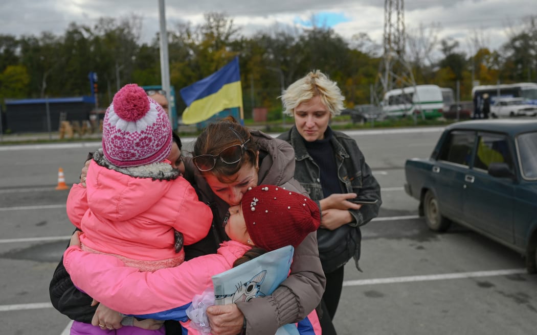 A Ukrainian woman (2nd L) are her children are welcomed by a relative after they were able to leave from Russian occupied territory of Kherson, in Zaporizhzhia, on October 21, 2022, amid Russia's invasion on Ukraine. (Photo by BULENT KILIC / AFP)