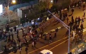 Men pull at a fence in a street in Tehran on Saturday, in a video released by Iran's Mehr News agency.