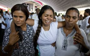 A grieving woman is supported during a funeral service attended by Cardinal Malcolm Ranjith for Easter Sunday bomb blast victims at St. Sebastian Church in Negombo, Sri Lanka, Tuesday, April 23, 2019.