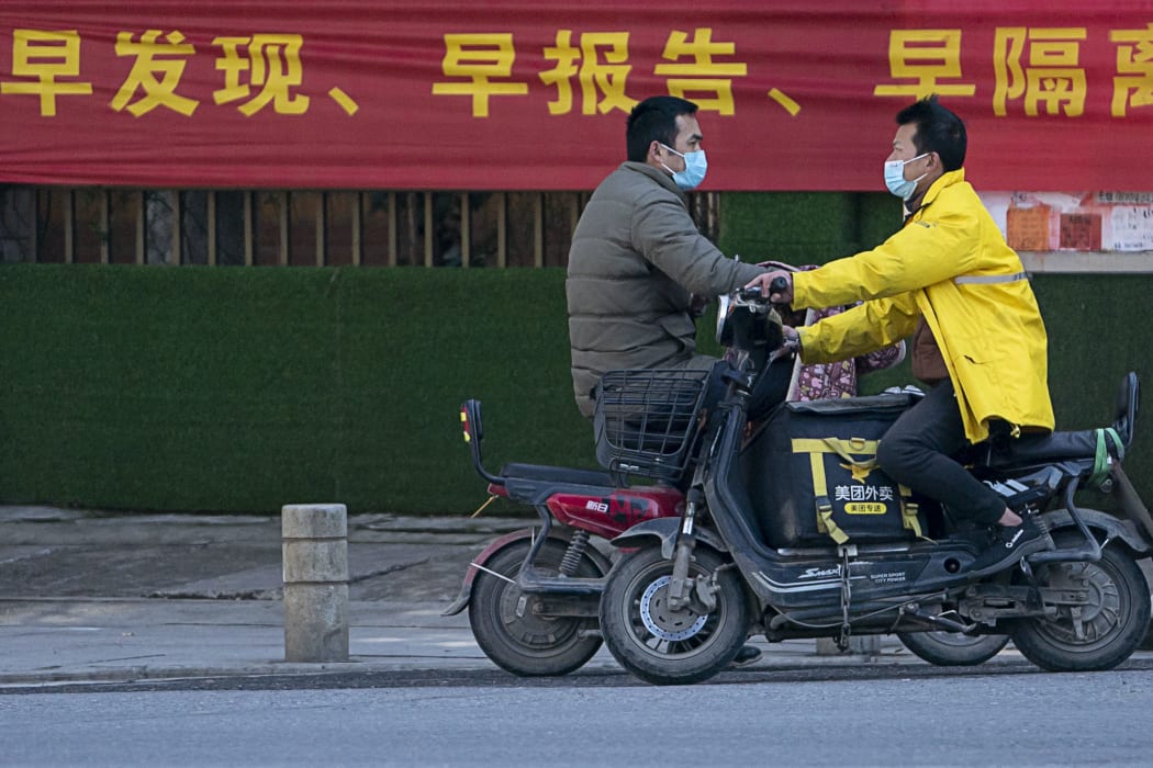 People ride scooters in a street in Wuhan,  Hubei Province, 16 February2020.