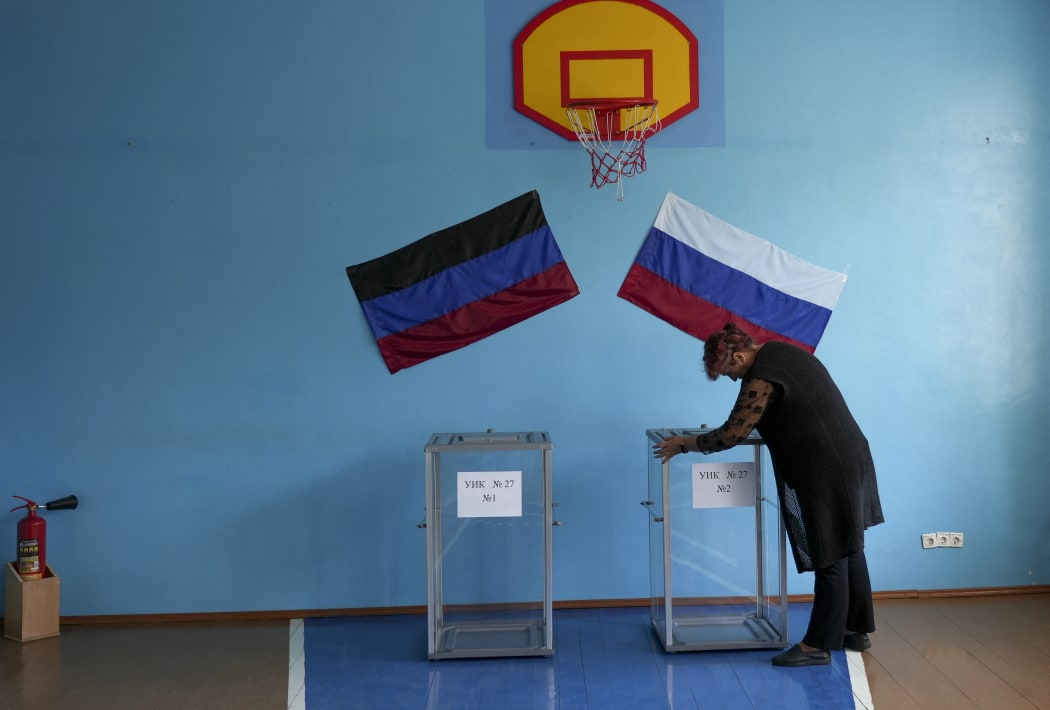 DONETSK OBLAST, UKRAINE - SEPTEMBER 24: A woman hangs flags as people cast their votes in controversial referendums  in Donetsk Oblast, Ukraine on September 24, 2022. Voting will run from Friday to Tuesday in Luhansk, Donetsk, Kherson and Zaporizhzhia, with people asked to decide if they want these regions to become part of Russia. Stringer / Anadolu Agency (Photo by STRINGER / ANADOLU AGENCY / Anadolu Agency via AFP)