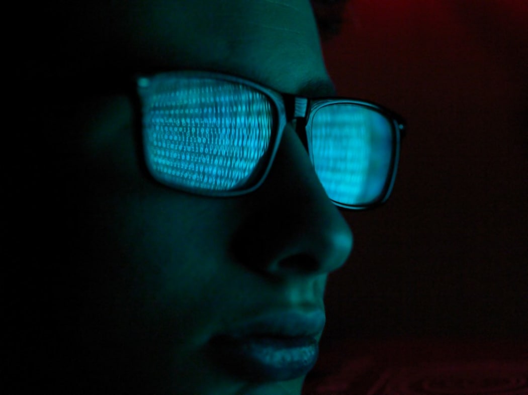 Cyber Crime, reflection in spectacles of virus hacking a computer, close up of face (Photo by Andrew Brookes / Cultura Creative / Cultura Creative via AFP)