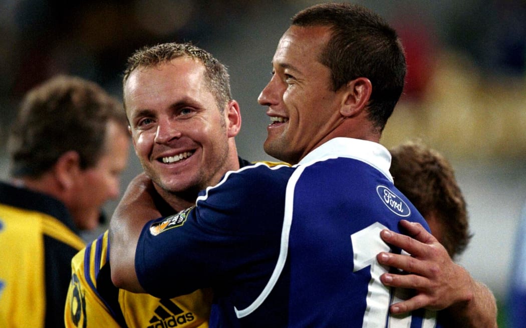 Blues player Carlos Spencer hugs the Hurricanes' Christian Cullen after the match between the Hurricanes and the Blues, 22 February, 2002.