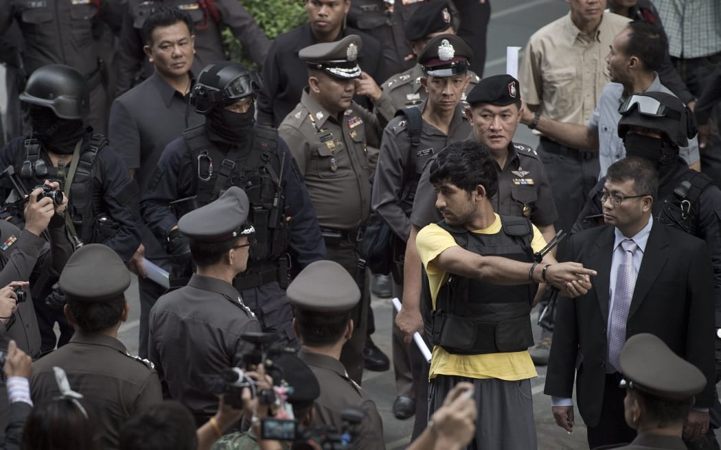 Erawan shrine bombing suspect Yusufu Mieraili during a reenactment, surrounded by police.