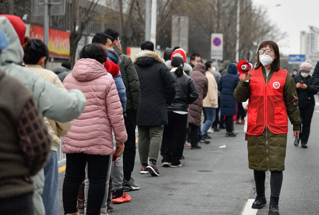 A volunteer gives citizens tips on nucleic acid test at a testing site in Nankai District, north China's Tianjin.