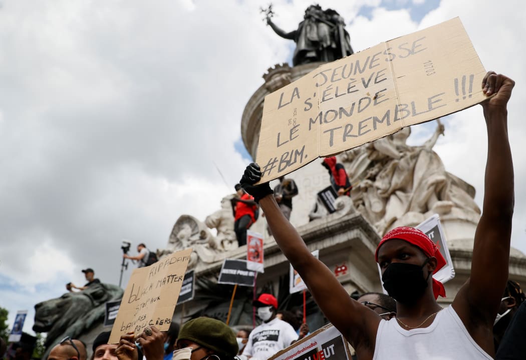 A protester wearing a protective face mask, holds a placard reading 'youth rises, the world trembles' during a rally in Paris.