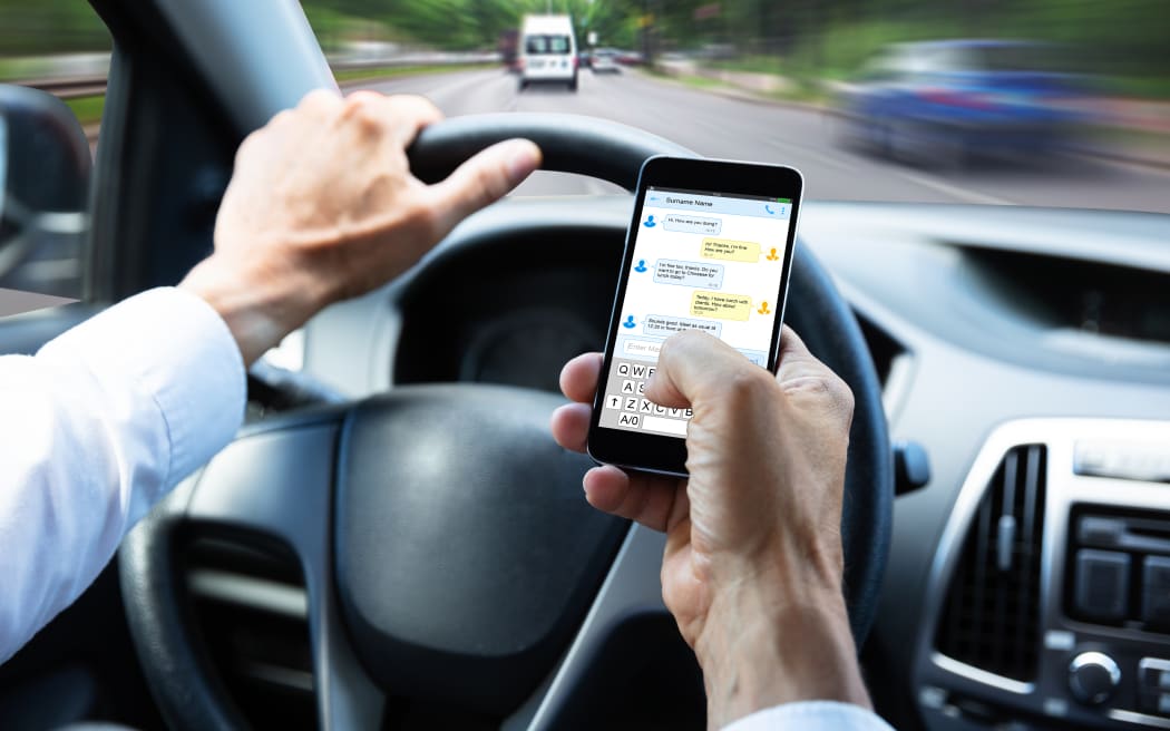 Close-up Of A Man's Hand Typing Text Message On Mobile Phone While Driving Car