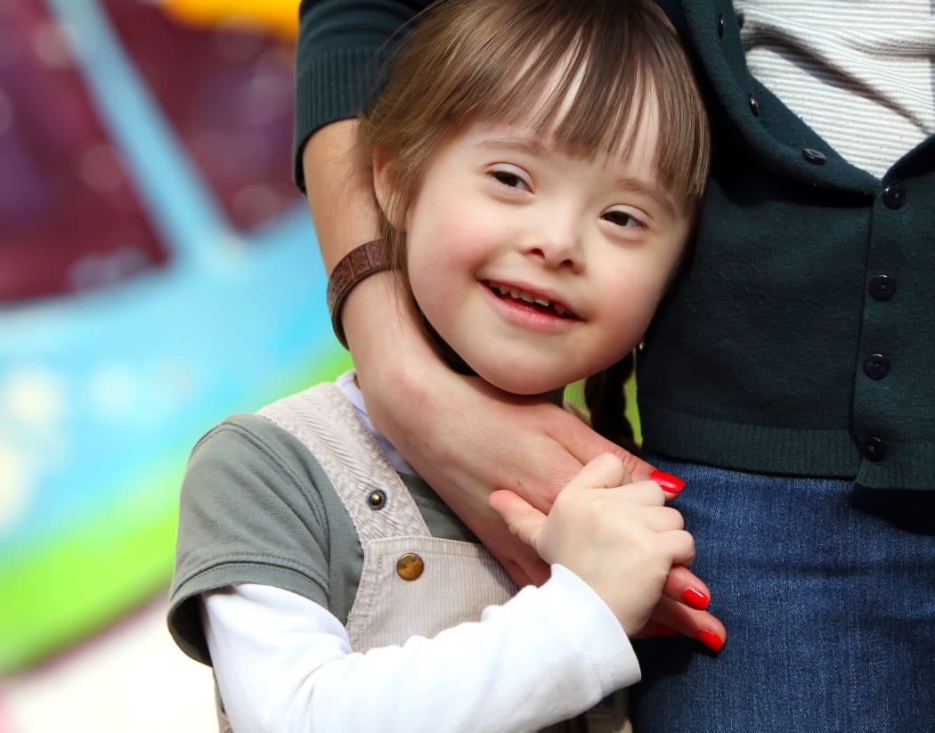 Close up of girl beign cuddled against her mother's hip