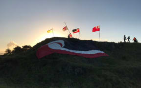 The tino rangatiratanga flag is seen at Ihumātao as the day draws to an end for protesters on the land on Friday, 26 July.