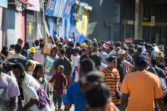 People carry items as crowds leave shops with looted goods amid a state of unrest in Port Moresby on January 10, 2024. A festering pay dispute involving Papua New Guinea's security forces on January 10 sparked angry protests in the capital, where a crowd torched a police car outside the prime minister's office. By Wednesday afternoon pockets of unrest had spread through the capital Port Moresby, with video clips on social media showing crowds looting shops and stretched police scrambling to restore order. (Photo by Andrew KUTAN / AFP)