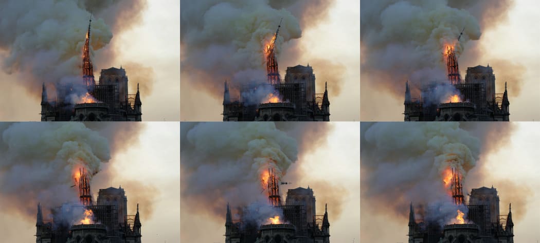 The steeple of Notre Dame Cathedral is engulfed in flames and collapses as the roof burns.
