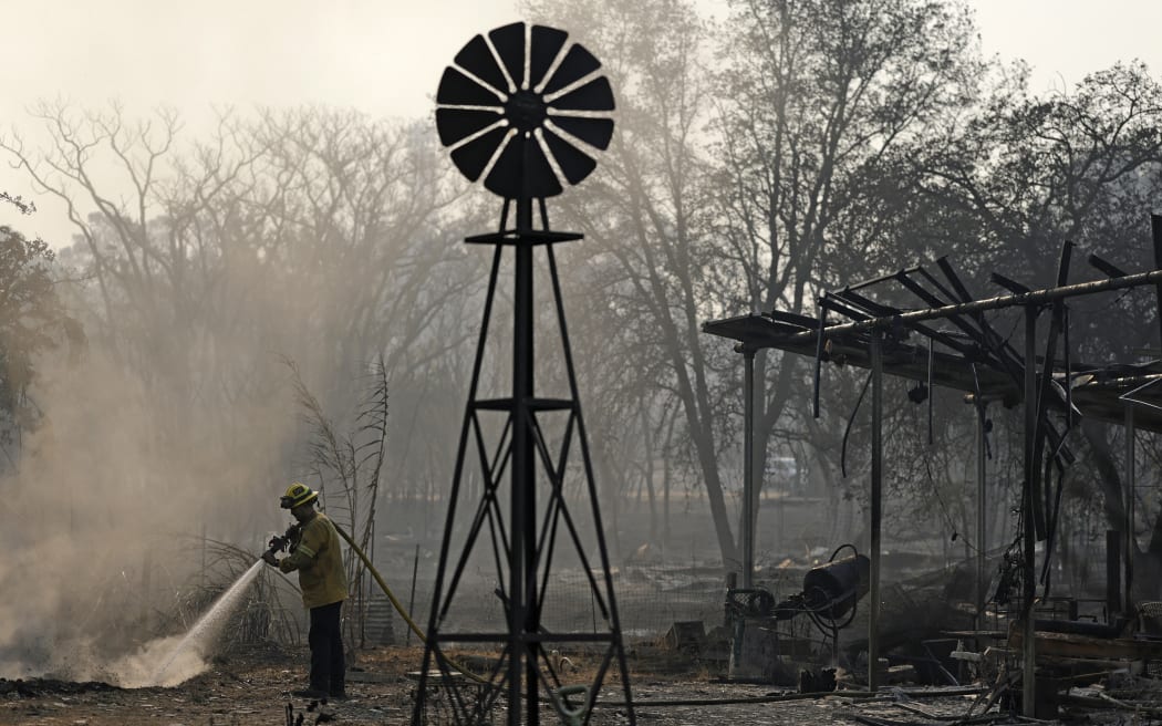 CHINESE CAMP, CALIFORNIA - SEPTEMBER 03: A Cal Fire firefighter sprays water on hot spots on a property that was burned by the 6-5 Fire in the TCU September Lightning Complex on September 03, 2025 in Chinese Camp, California. Nearly 12,000 acres have burned, and several structures were destroyed in the historic gold rush town of Chinese Camp after the 6-5 Fire, which is part of the TCU September Lightning Complex, a series of at least nine fires that were sparked by lightning. The TCU Lightning Complex is currently zero percent contained.   Justin Sullivan/Getty Images/AFP (Photo by JUSTIN SULLIVAN / GETTY IMAGES NORTH AMERICA / Getty Images via AFP)