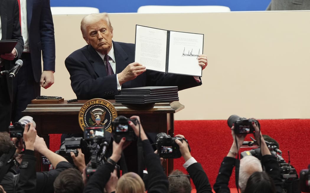Trump holds an executive order after signing it at an inauguration event in Washington, DC, on Monday.
