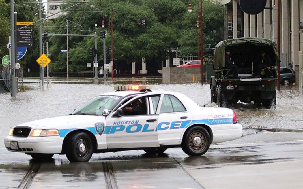 A Houston police officer blocks a flooded street as emergency services look for people stranded in downtown Houston.