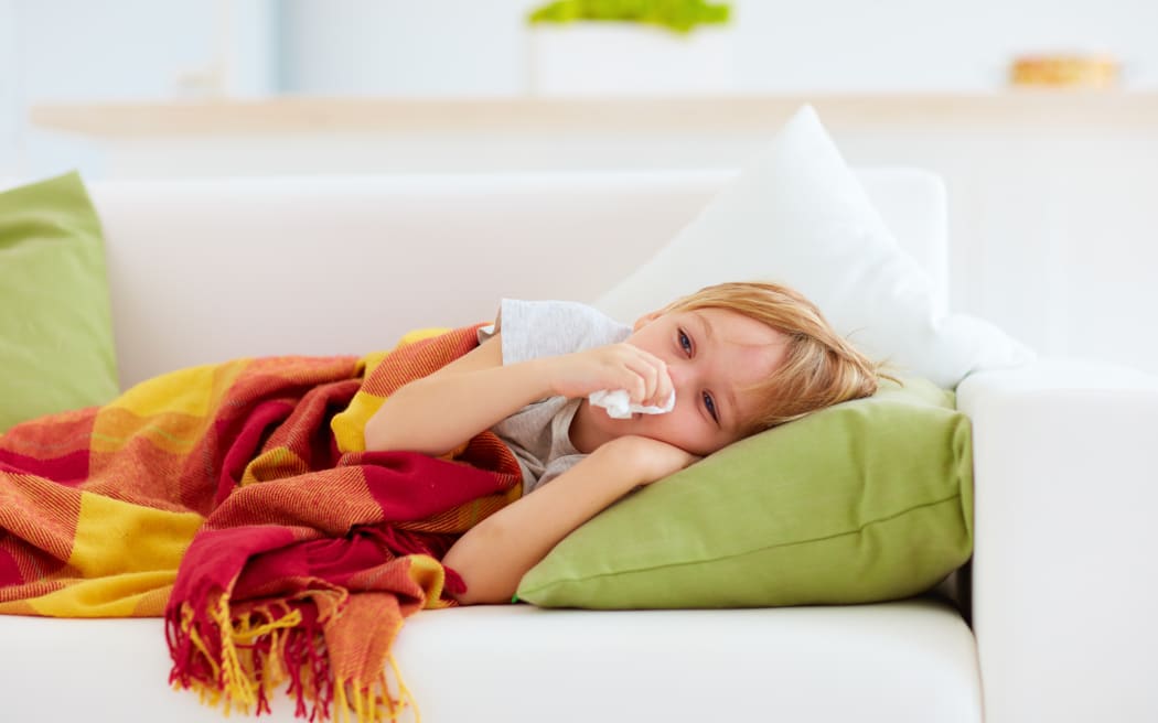 sick kid with runny nose and fever heat lying on couch at home