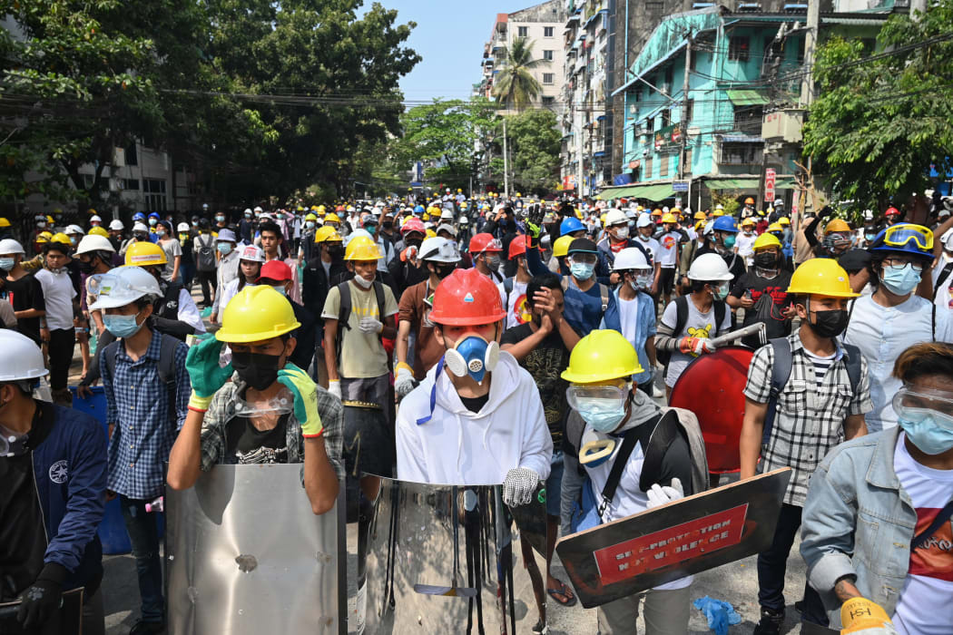 Protesters wearing protective gear gather on a road during a demonstration against the military coup in Yangon on 3 March