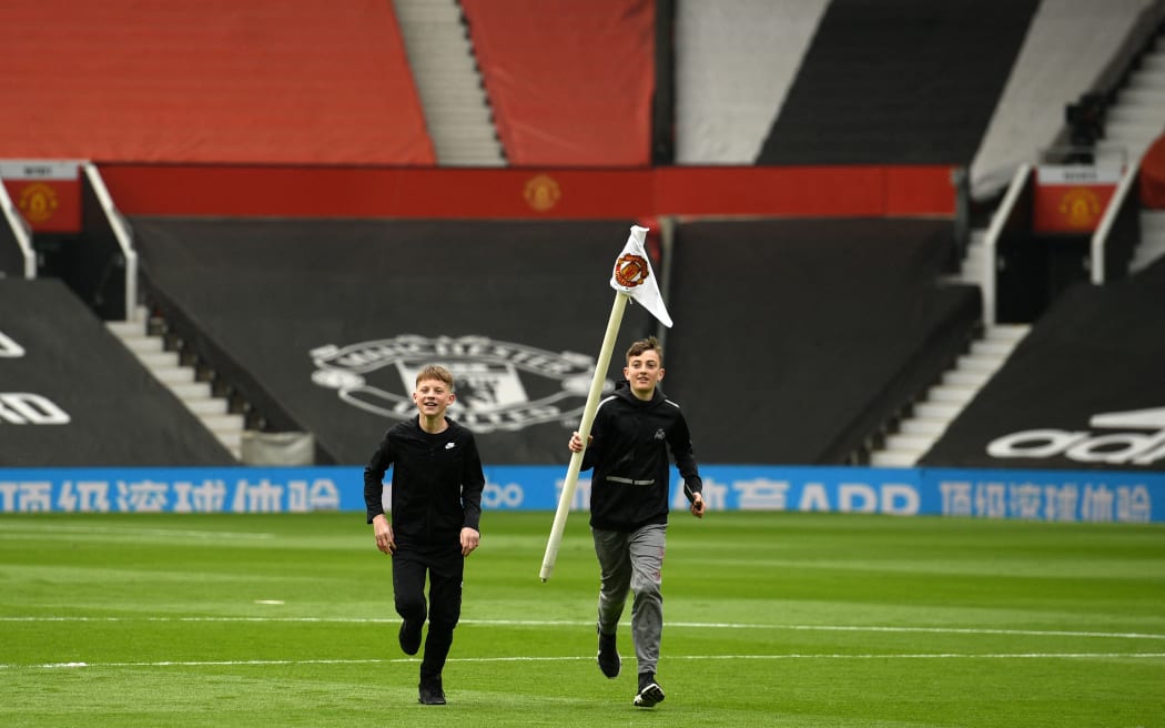 A young fan walks away with a corner flag as supporters protest against Manchester United's owners, inside English Premier League club Manchester United's Old Trafford stadium in Manchester, north west England on May 2, 2021, ahead of their English Premier League fixture against Liverpool.