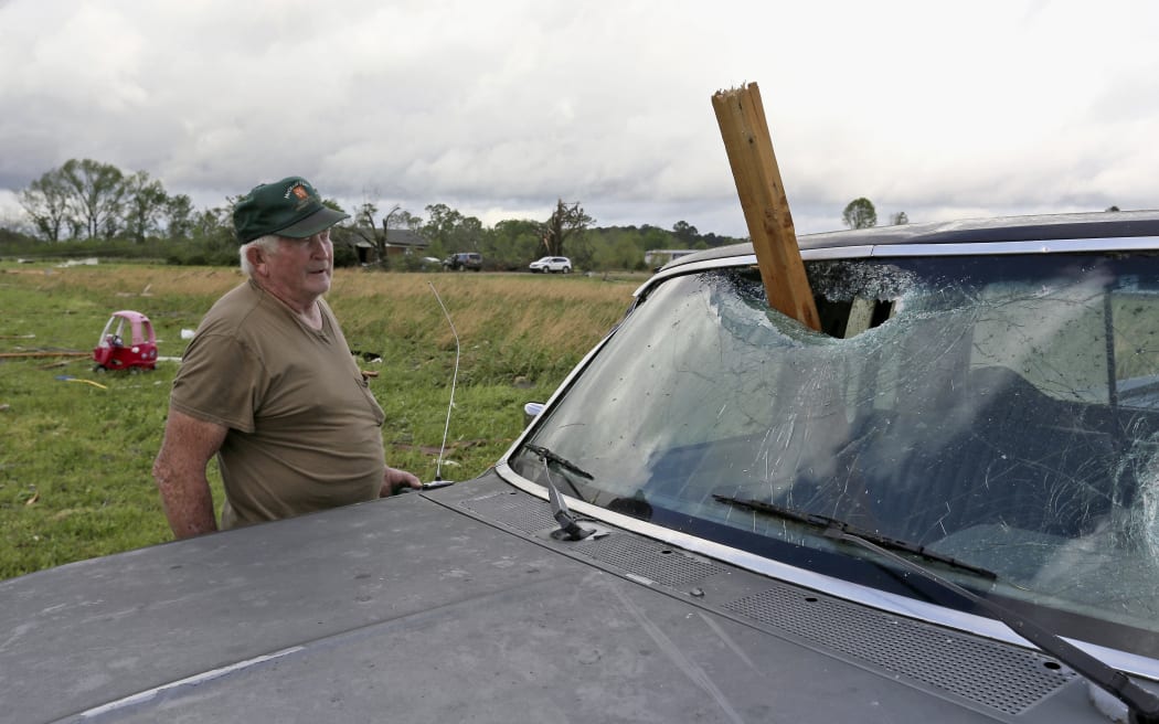 A man looks at a piece of wood that was blown through the windshield of his daughter's truck in Hamilton, Miss., after a storm moved through the area Sunday, April 14, 2019.
