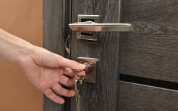 Woman opening wooden door with key indoors, closeup