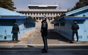 A South Korean soldier (C) stands guard before the military demarcation line and North Korea's Panmun Hall, in the truce village of Panmunjom, within the Demilitarized Zone (DMZ) dividing the two Koreas on February 21, 2018. / AFP PHOTO / Ed JONES