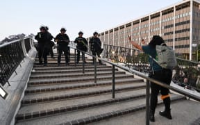 A protestor makes a rude gesture towards LAPD officers as she has to clear the area as curfew is in effect after days of protests in response to federal immigration operations in Los Angeles.